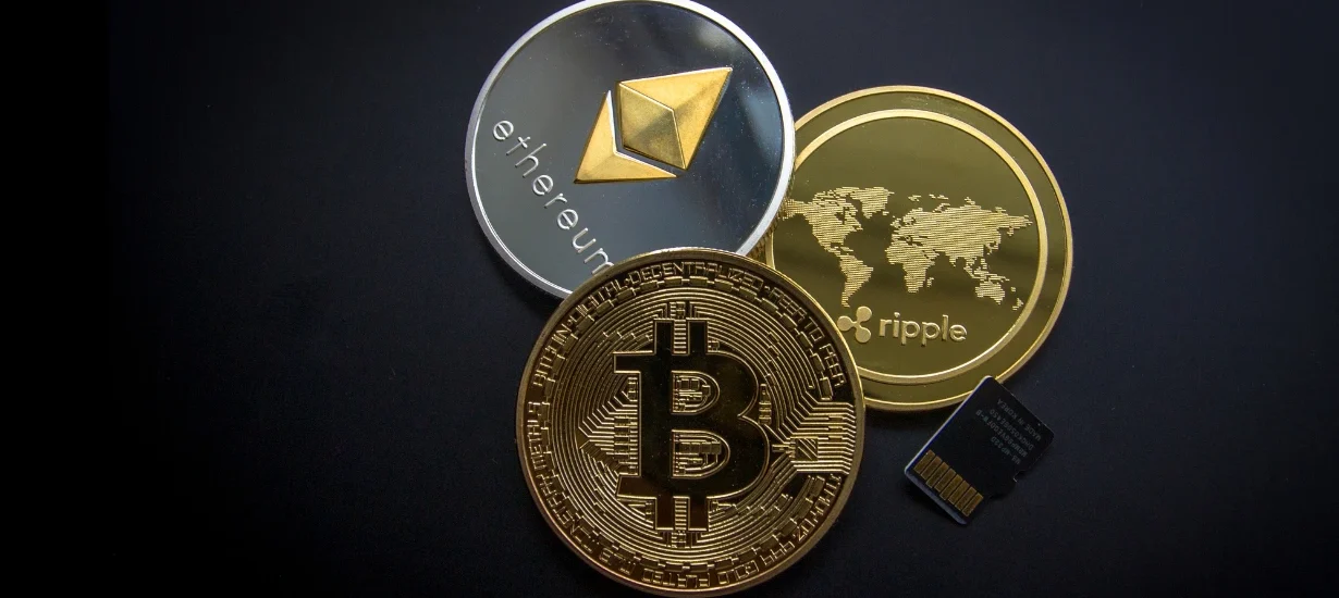 Imagem conceitual com moedas digitais representando Ethereum, Bitcoin e Ripple sobre fundo preto, simbolizando a infraestrutura da nova engenharia financeira global operando 24h por dia.