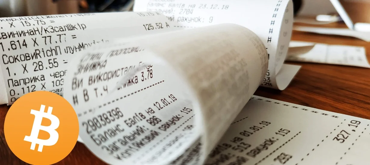 Bobina de notas fiscais ao lado do símbolo do Bitcoin, representando transações comerciais com criptoativos