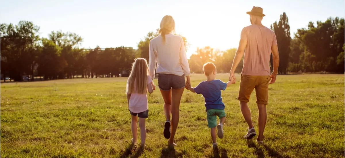 Família de quatro pessoas de mãos dadas ao pôr do sol, representando sucessão patrimonial com segurança em criptoativos