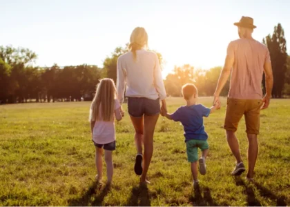 Família de quatro pessoas de mãos dadas ao pôr do sol, representando sucessão patrimonial com segurança em criptoativos