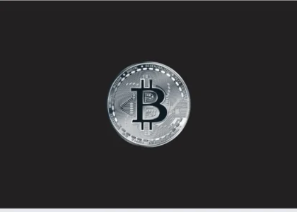 Símbolo de Bitcoin prateado em destaque sobre fundo escuro, representando herança digital e planejamento com criptoativos