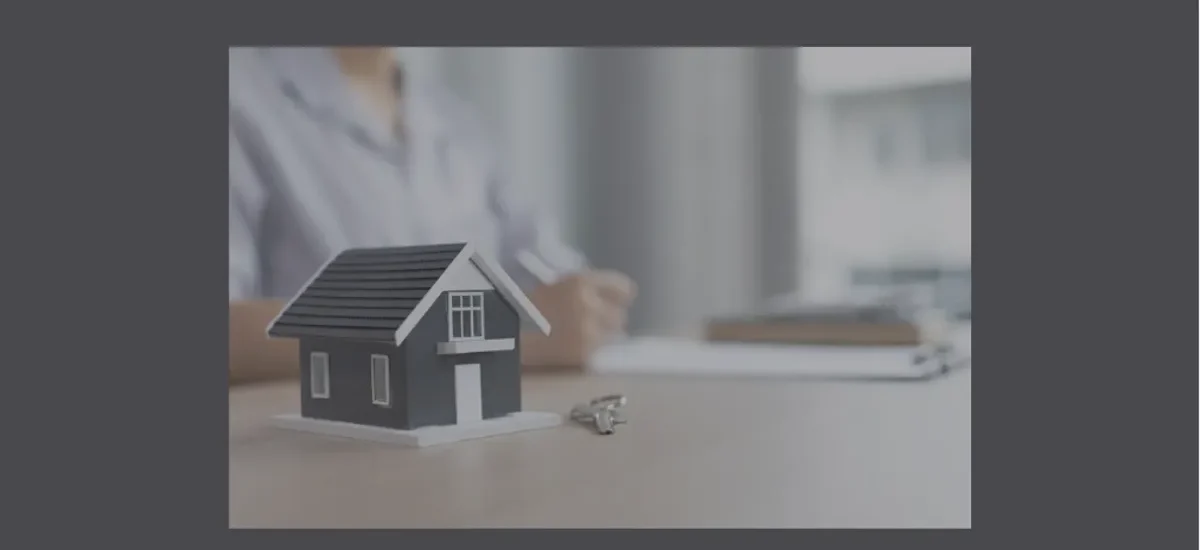 Miniatura de casa com chaves sobre a mesa e pessoa ao fundo, simbolizando análise de vantagens e desvantagens de imóveis tokenizados