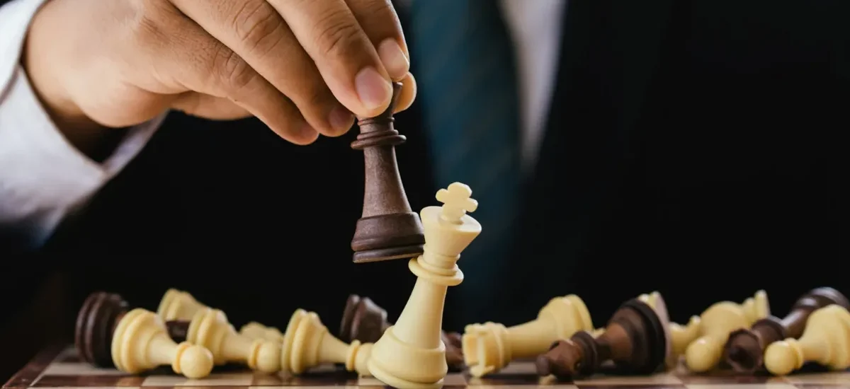 Mão derrubando rei no jogo de xadrez como símbolo de estratégia e vitória"