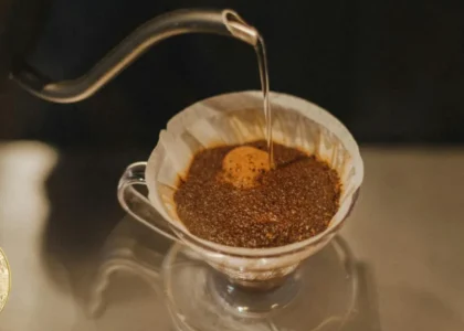 Café sendo preparado com filtro e moeda Bitcoin ilustrando pagamento de pequenas compras com cripto